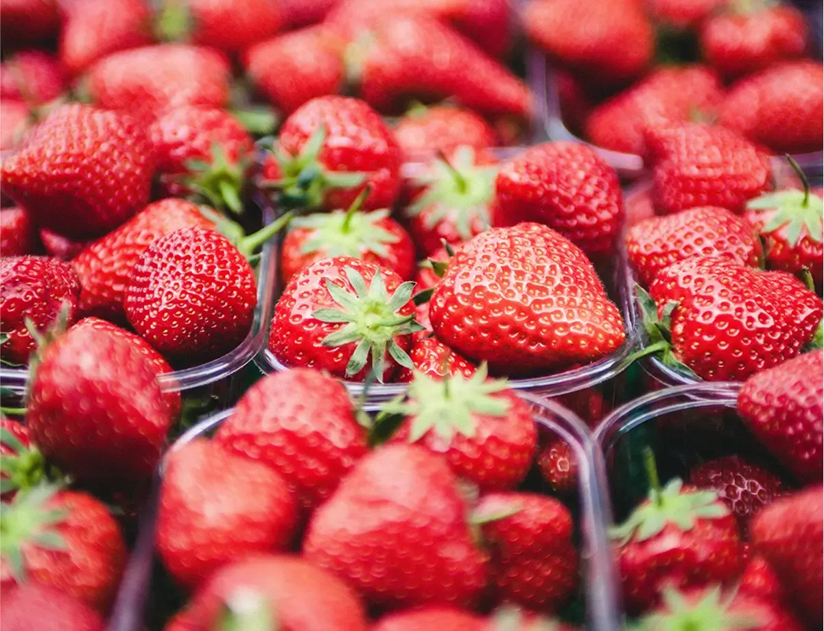 Close-up of fresh red strawberries in plastic containers at a market